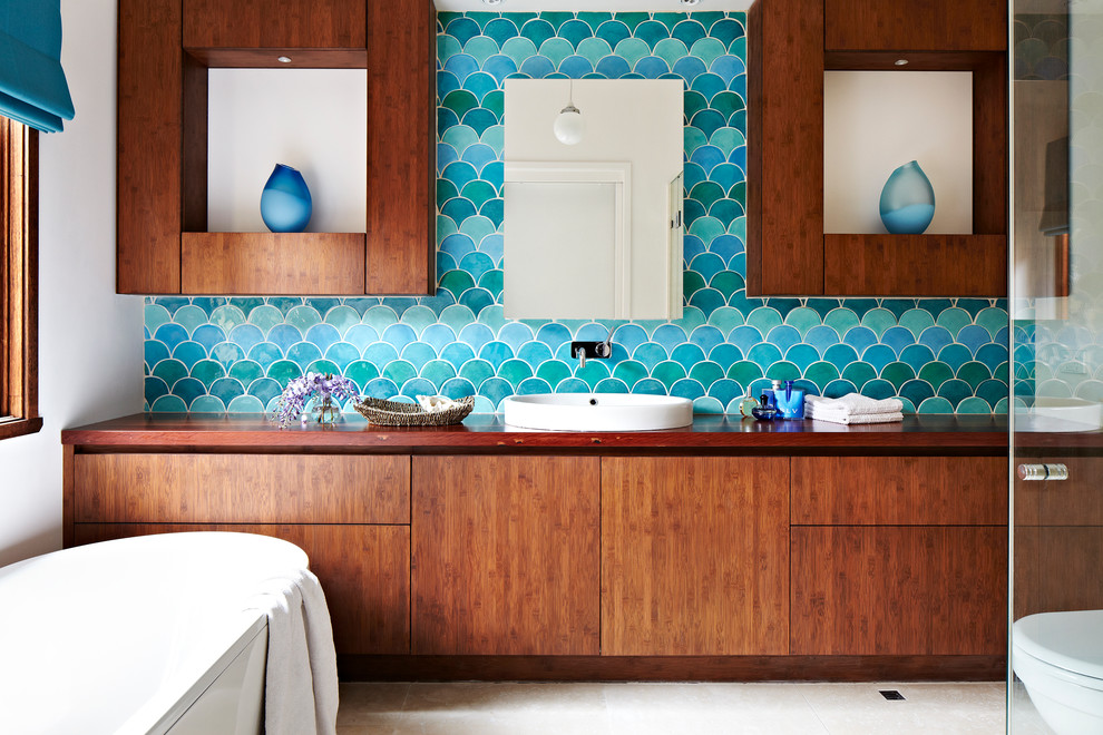Idées déco pour une salle de bain principale contemporaine en bois brun avec une vasque, un placard à porte plane, un plan de toilette en bois, une baignoire indépendante, un carrelage bleu, un mur bleu et un plan de toilette marron.