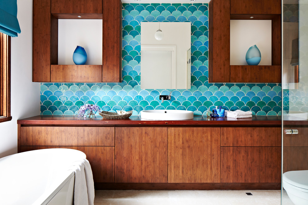 Freestanding bathtub - contemporary master blue tile freestanding bathtub idea in Melbourne with a vessel sink, flat-panel cabinets, medium tone wood cabinets, wood countertops, blue walls and brown countertops