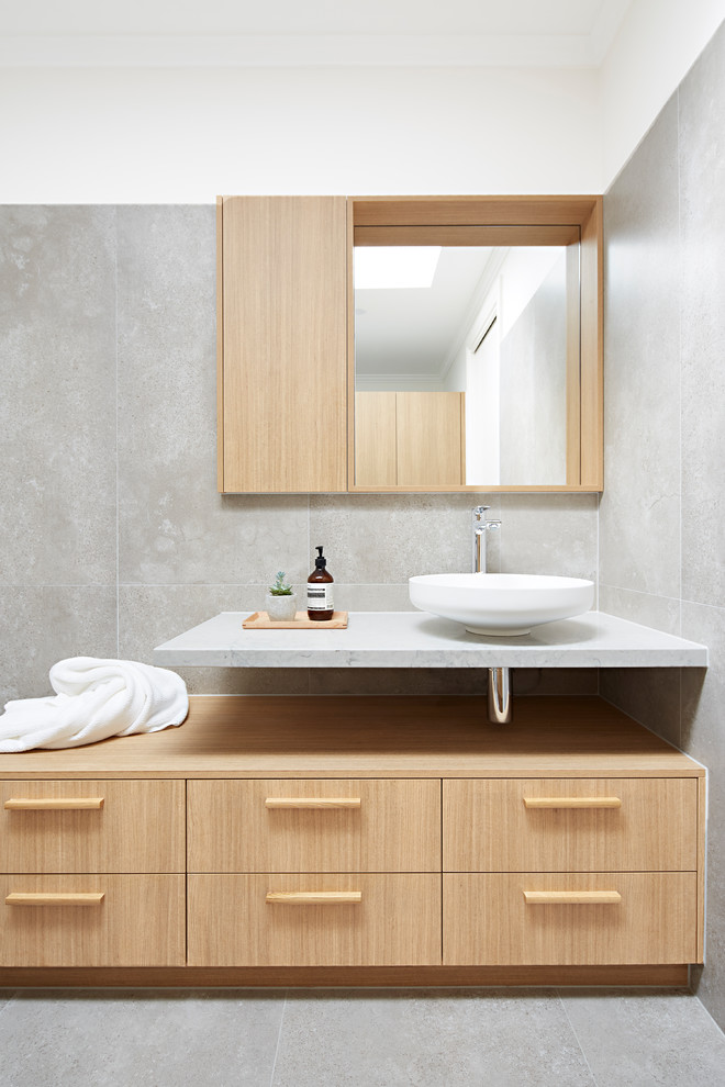 Inredning av ett modernt mellanstort vit vitt en-suite badrum, med skåp i ljust trä, ett fristående handfat, grått golv, luckor med profilerade fronter, en dusch i en alkov, en vägghängd toalettstol, flerfärgad kakel, stenhäll, flerfärgade väggar, marmorbänkskiva och med dusch som är öppen