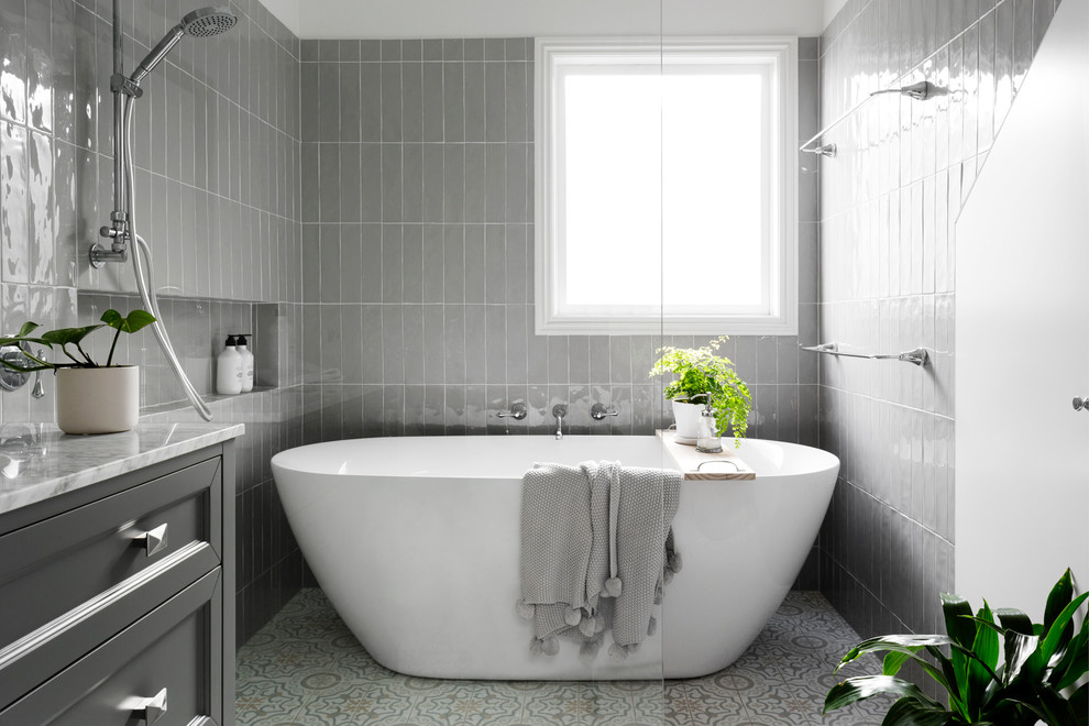 Photo of a classic bathroom in Melbourne with recessed-panel cabinets, grey cabinets, a freestanding bath, a built-in shower, grey tiles, grey walls, multi-coloured floors, an open shower and white worktops.