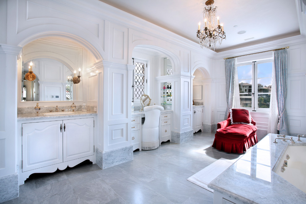 Foto di una stanza da bagno mediterranea con ante con bugna sagomata, ante bianche, vasca sottopiano, piastrelle grigie e top grigio