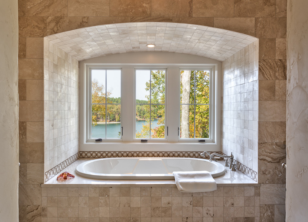 Large tuscan limestone tile drop-in bathtub photo in Other with shaker cabinets, dark wood cabinets and an undermount sink