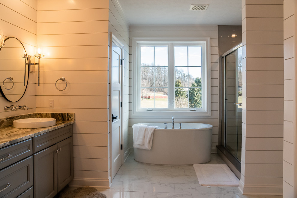 Idée de décoration pour une salle de bain style shabby chic avec un placard avec porte à panneau surélevé, des portes de placard grises, une baignoire indépendante, une douche double, des carreaux de céramique, un sol en carrelage de céramique, une vasque, un plan de toilette en granite, un sol blanc, une cabine de douche à porte coulissante, un banc de douche, meuble double vasque, meuble-lavabo encastré et du lambris de bois.