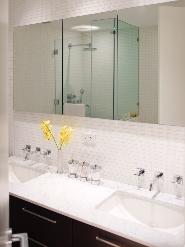 Small modern ensuite bathroom in New York with flat-panel cabinets, black cabinets, a corner shower, a one-piece toilet, white tiles, mosaic tiles, white walls, a submerged sink, marble worktops, a hinged door and white worktops.