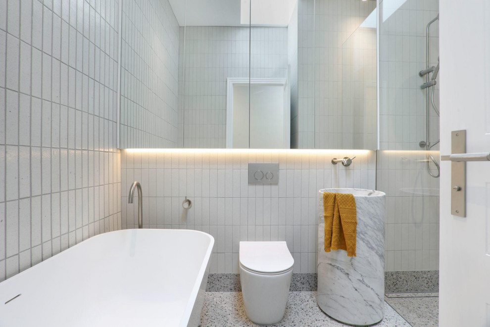 Ispirazione per una stanza da bagno moderna con vasca freestanding, doccia alcova, WC monopezzo, piastrelle bianche, lavabo a colonna e pavimento grigio