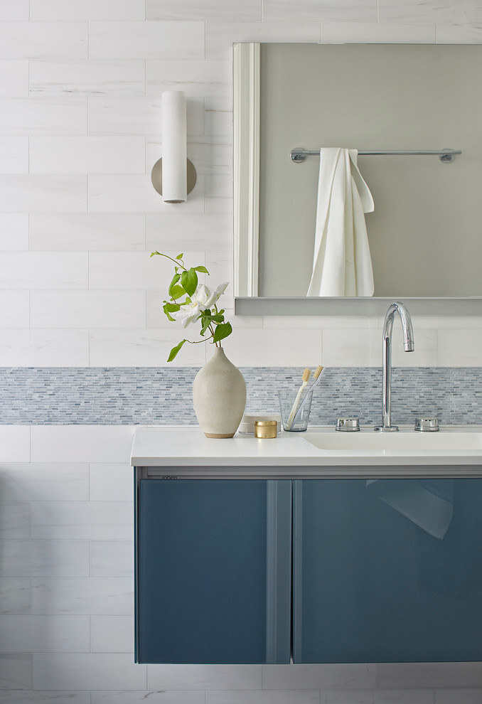 Foto di una stanza da bagno padronale design di medie dimensioni con ante lisce, ante blu, piastrelle bianche, piastrelle in ceramica, pareti bianche, lavabo sospeso e top in marmo
