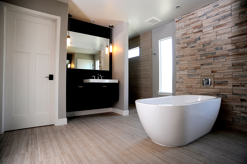 Modern inredning av ett vit vitt badrum, med svarta skåp, ett fristående badkar, beige kakel, porslinskakel, grå väggar, klinkergolv i porslin och beiget golv