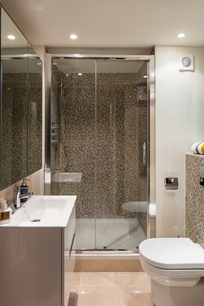 This is an example of a medium sized contemporary ensuite bathroom in Dublin with flat-panel cabinets, white cabinets, an alcove shower, a wall mounted toilet, beige tiles, porcelain tiles, beige walls, porcelain flooring and a built-in sink.