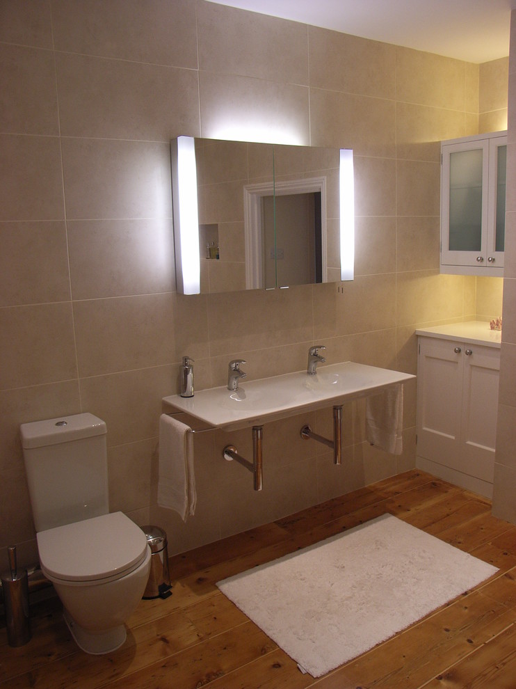 Inspiration for a medium sized contemporary ensuite bathroom in Other with a wall-mounted sink, raised-panel cabinets, white cabinets, wooden worktops, a two-piece toilet, beige tiles, porcelain tiles and light hardwood flooring.