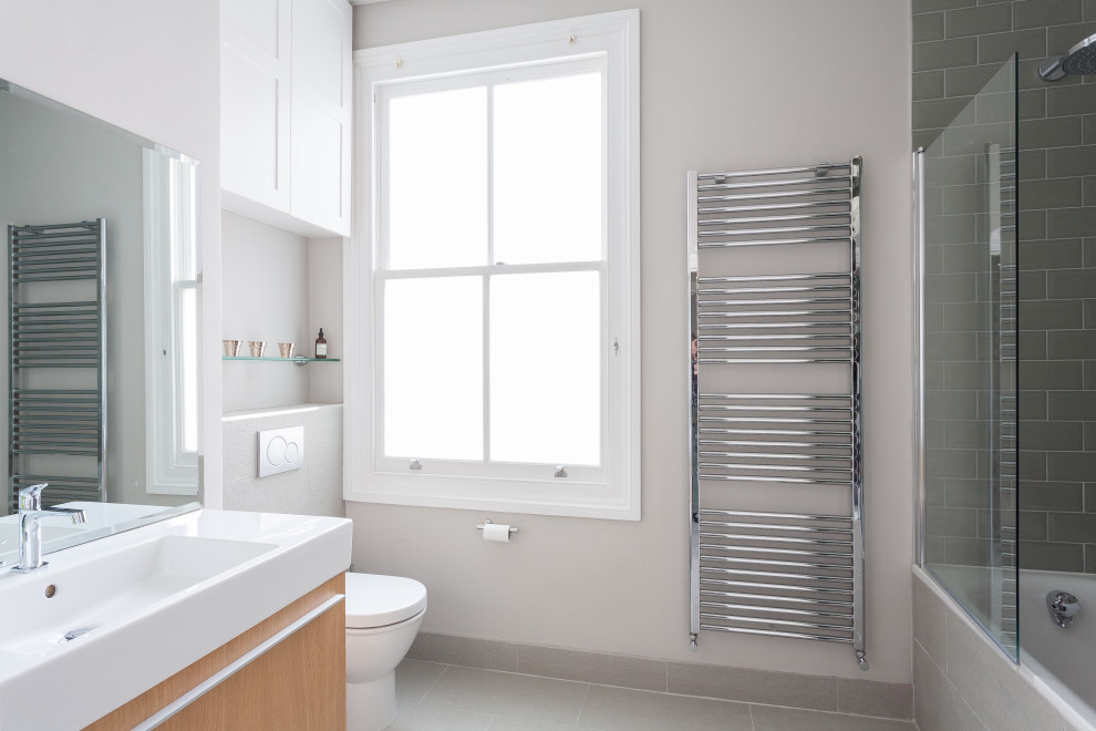 Bild på ett litet funkis vit vitt en-suite badrum, med släta luckor, skåp i ljust trä, ett platsbyggt badkar, en dusch/badkar-kombination, beige kakel, beige väggar och bänkskiva i täljsten