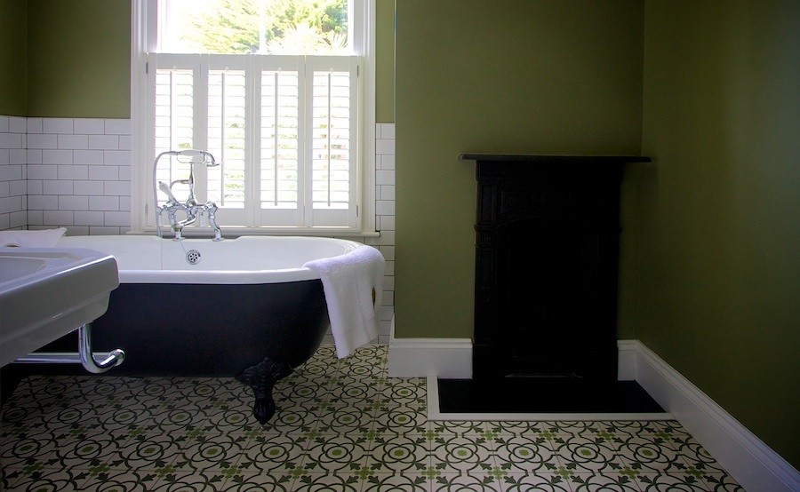 Inredning av ett klassiskt mellanstort badrum för barn, med ett piedestal handfat, ett badkar med tassar, en toalettstol med separat cisternkåpa, grön kakel, cementkakel och gröna väggar