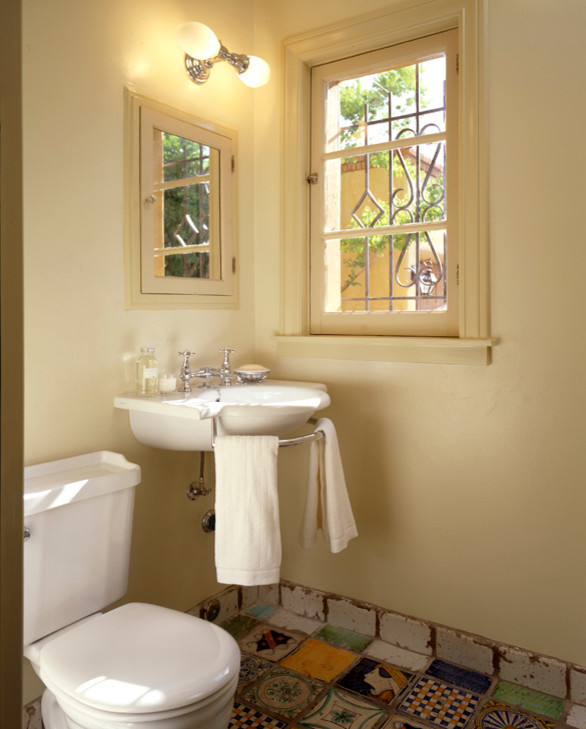 Cette image montre une petite salle d'eau méditerranéenne avec un lavabo de ferme, WC séparés, un carrelage multicolore, des carreaux de béton, un mur jaune et tomettes au sol.