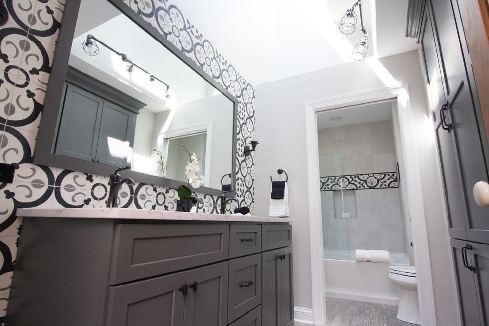 Стильный дизайн: большая главная ванная комната в стиле лофт с плоскими фасадами, серыми фасадами, ванной в нише, душем над ванной, раздельным унитазом, черно-белой плиткой, цементной плиткой, серыми стенами, полом из керамогранита, врезной раковиной, столешницей из искусственного кварца, серым полом, душем с распашными дверями и белой столешницей - последний тренд