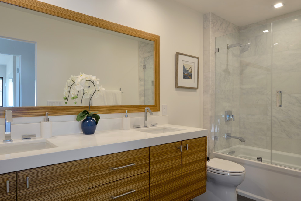 Inspiration for a medium sized modern family bathroom in San Diego with flat-panel cabinets, medium wood cabinets, an alcove bath, a shower/bath combination, white tiles, stone tiles, white walls, porcelain flooring, a submerged sink and engineered stone worktops.