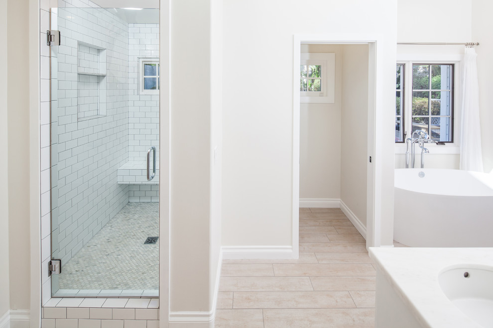 Bathroom - mid-sized traditional master white tile and porcelain tile porcelain tile and brown floor bathroom idea in San Diego with shaker cabinets, white cabinets, a two-piece toilet, white walls, an undermount sink, quartz countertops and a hinged shower door