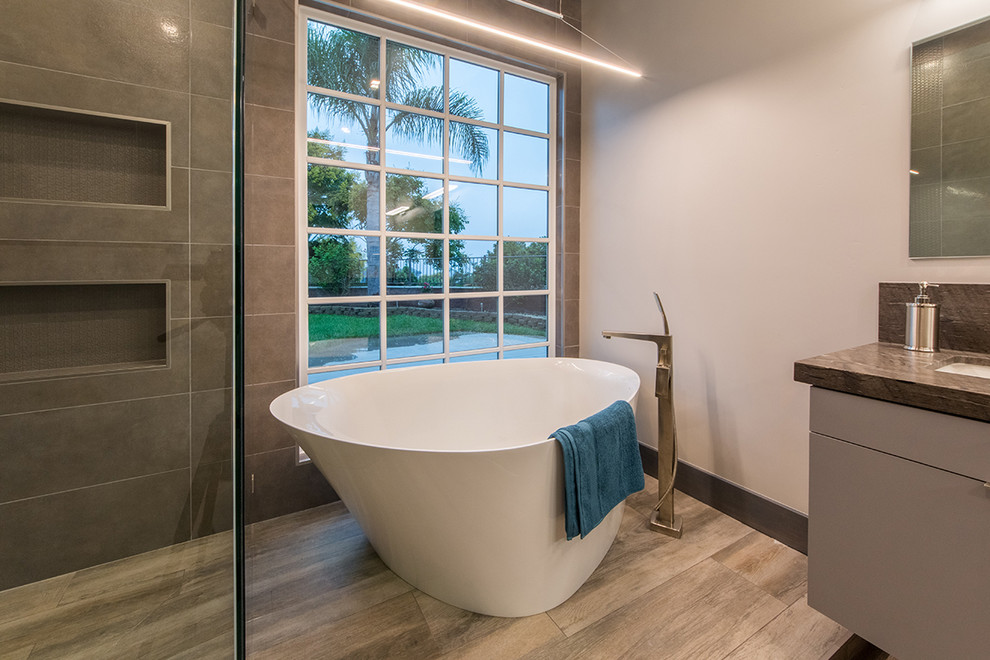 Inredning av ett modernt stort brun brunt en-suite badrum, med släta luckor, grå skåp, ett japanskt badkar, en öppen dusch, grå väggar, laminatgolv, ett undermonterad handfat, marmorbänkskiva, brunt golv och dusch med gångjärnsdörr