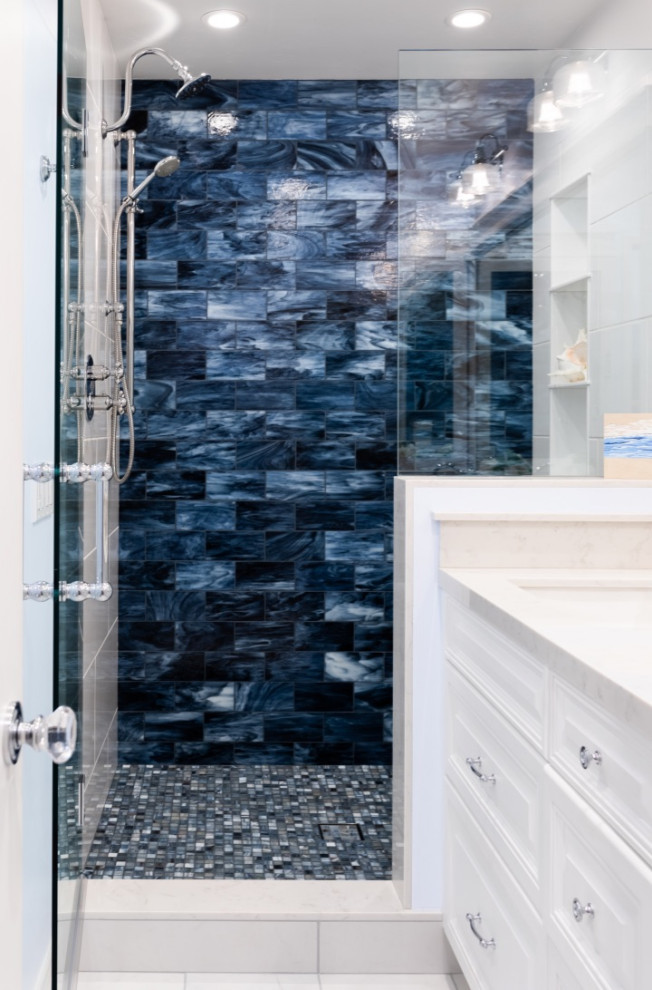 Example of a mid-sized beach style master blue tile and glass tile porcelain tile, white floor and double-sink alcove shower design in San Diego with raised-panel cabinets, white cabinets, blue walls, an undermount sink, quartz countertops, a hinged shower door, white countertops and a built-in vanity