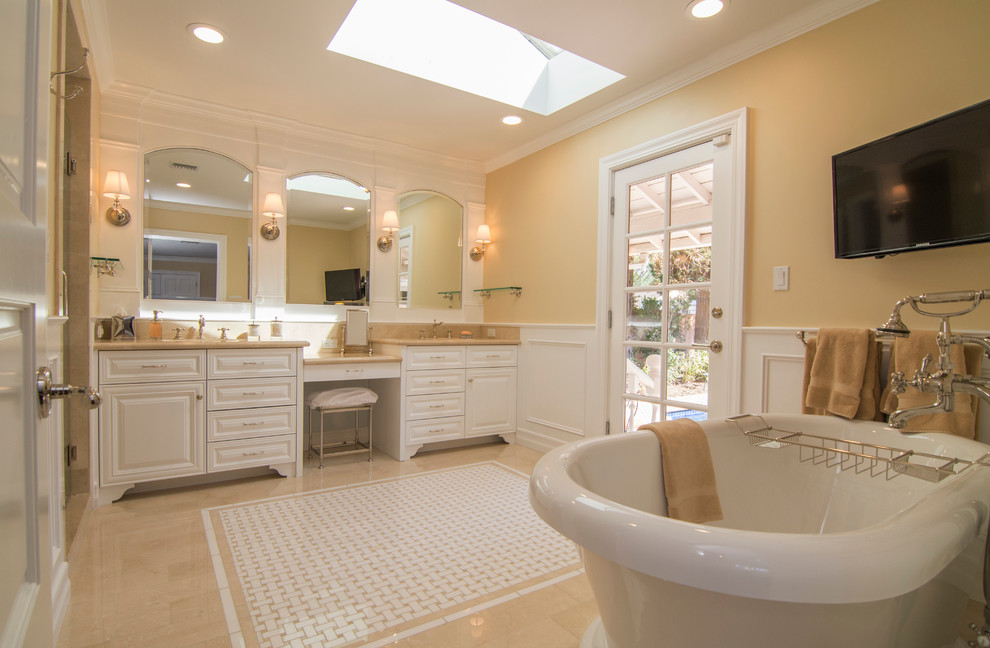 Photo of a medium sized classic ensuite bathroom in Los Angeles with a submerged sink, raised-panel cabinets, white cabinets, marble worktops, a corner shower, beige tiles, yellow walls, marble flooring, a freestanding bath, a one-piece toilet and stone tiles.