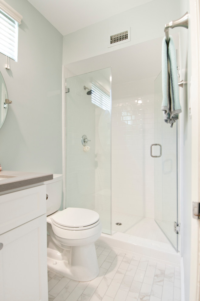Foto de cuarto de baño principal, tradicional renovado, de tamaño medio, con armarios estilo shaker, puertas de armario blancas, ducha empotrada, sanitario de dos piezas, baldosas y/o azulejos blancos, baldosas y/o azulejos de cerámica, paredes azules, suelo de mármol, lavabo bajoencimera, encimera de cuarcita, suelo blanco, ducha con puerta con bisagras y encimeras grises