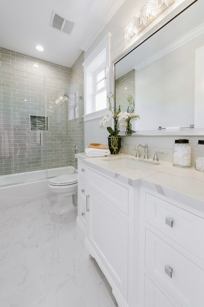 Inspiration for a small traditional bathroom in Los Angeles with beaded cabinets, white cabinets, an alcove bath, a shower/bath combination, a two-piece toilet, a submerged sink, quartz worktops, a hinged door and grey walls.