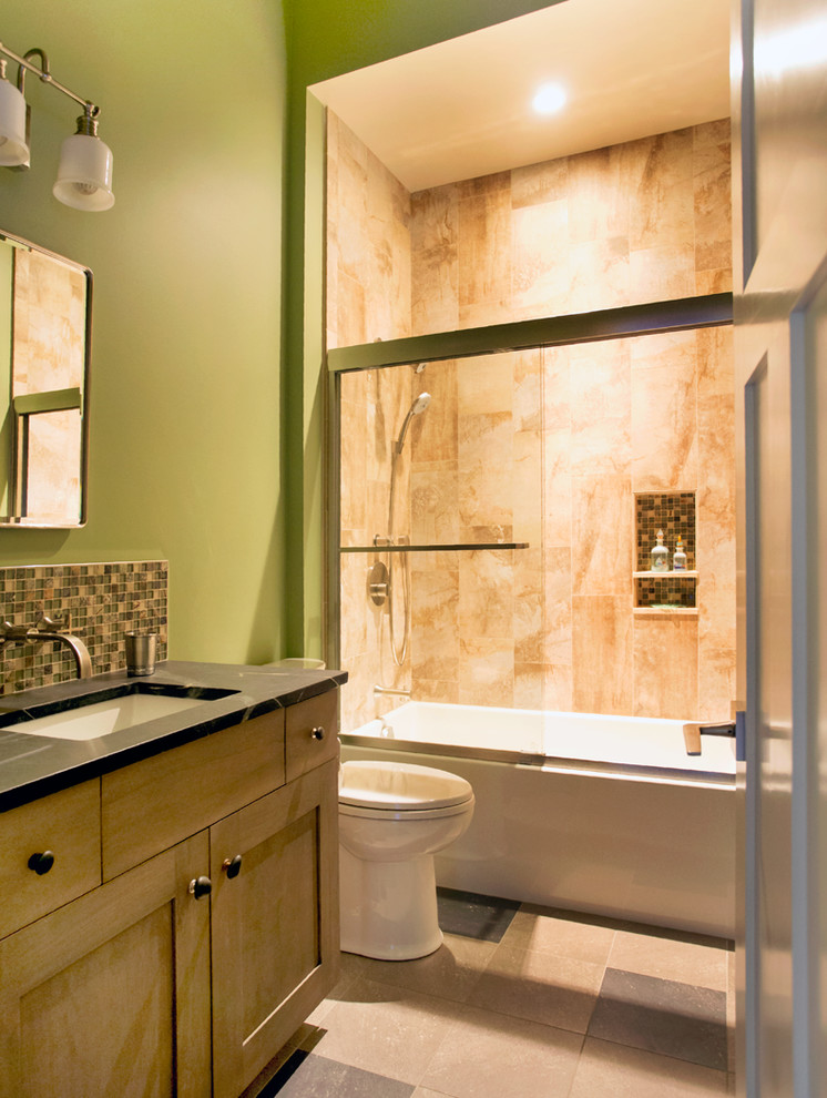 На фото: главная ванная комната среднего размера в стиле неоклассика (современная классика) с фасадами с утопленной филенкой, светлыми деревянными фасадами, душем над ванной, раздельным унитазом, разноцветной плиткой, зелеными стенами, полом из керамогранита, ванной в нише, стеклянной плиткой, врезной раковиной, столешницей из талькохлорита, разноцветным полом, душем с раздвижными дверями и черной столешницей
