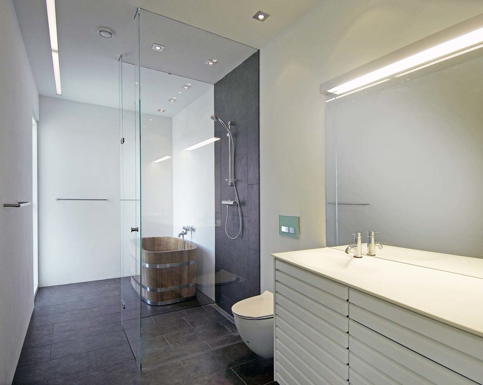 Foto di una stanza da bagno padronale minimal con ante bianche, vasca freestanding, doccia aperta, WC sospeso, piastrelle nere e pareti bianche