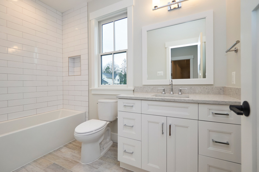 Exemple d'une salle de bain chic de taille moyenne avec un placard à porte shaker, des portes de placard blanches, une baignoire en alcôve, WC séparés, des carreaux de céramique, un mur blanc, un sol en carrelage de porcelaine, un lavabo encastré, un plan de toilette en quartz modifié, un sol gris, une cabine de douche avec un rideau, un plan de toilette gris, une niche, meuble simple vasque, meuble-lavabo encastré et un carrelage blanc.
