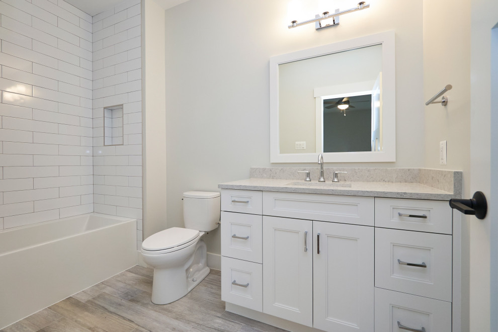 Пример оригинального дизайна: детская ванная комната среднего размера в стиле неоклассика (современная классика) с фасадами в стиле шейкер, белыми фасадами, ванной в нише, душем в нише, раздельным унитазом, керамической плиткой, белыми стенами, полом из керамогранита, врезной раковиной, столешницей из искусственного кварца, серым полом, шторкой для ванной, серой столешницей, нишей, тумбой под одну раковину, встроенной тумбой и белой плиткой