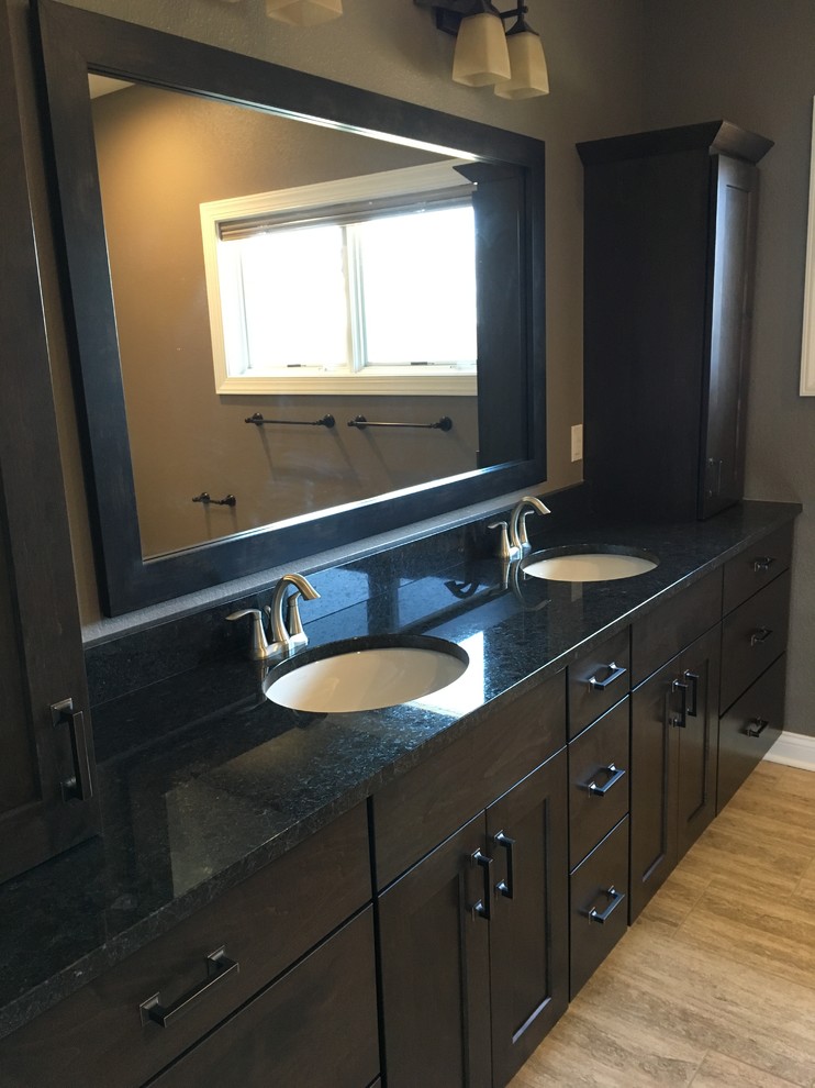 Inspiration for a large contemporary master beige tile and porcelain tile light wood floor and beige floor corner shower remodel in Milwaukee with recessed-panel cabinets, dark wood cabinets, gray walls, an undermount sink, granite countertops and a hinged shower door