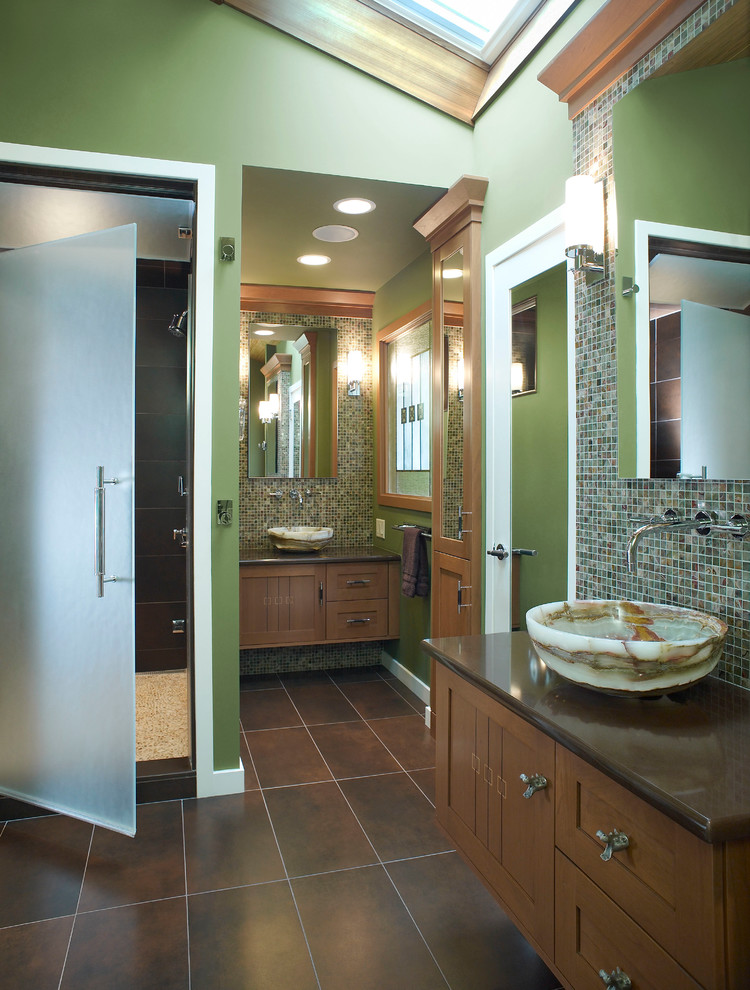 Cette photo montre une douche en alcôve principale craftsman en bois brun de taille moyenne avec une vasque, un placard à porte shaker, un plan de toilette en surface solide, un carrelage multicolore, mosaïque, un mur vert et un sol en carrelage de porcelaine.