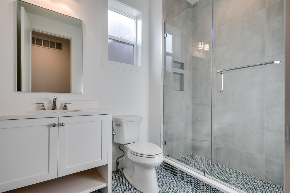 Inspiration for a mid-sized transitional 3/4 gray tile and porcelain tile porcelain tile and blue floor bathroom remodel in Denver with shaker cabinets, white cabinets, a two-piece toilet, white walls, an undermount sink, quartz countertops, a hinged shower door and white countertops