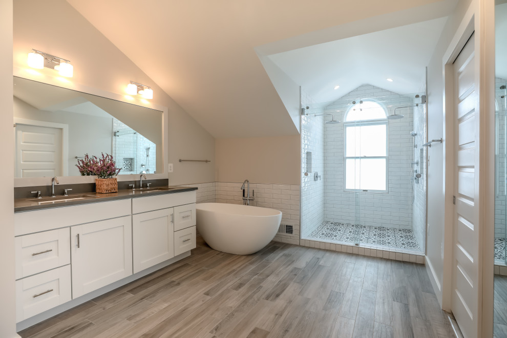 Photo of a medium sized contemporary ensuite bathroom in DC Metro with white cabinets, a freestanding bath, a double shower, white tiles, ceramic tiles, beige walls, granite worktops and black worktops.