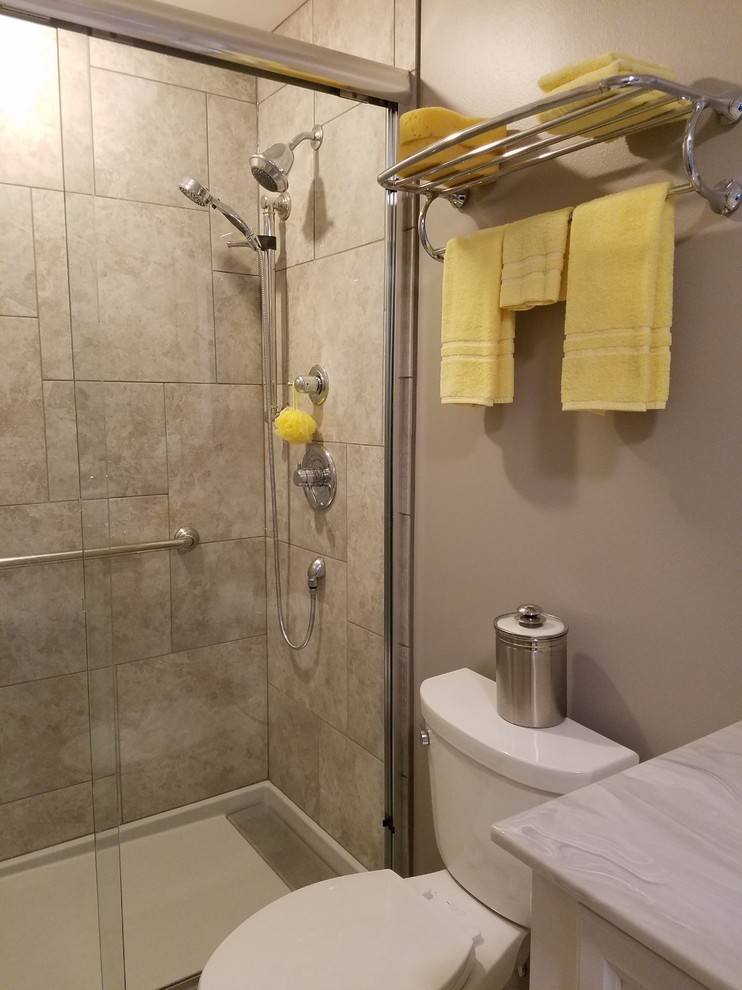 This is an example of a medium sized traditional ensuite bathroom in Other with recessed-panel cabinets, white cabinets, an alcove shower, a two-piece toilet, beige tiles, ceramic tiles, beige walls, ceramic flooring, an integrated sink, marble worktops, beige floors and a sliding door.
