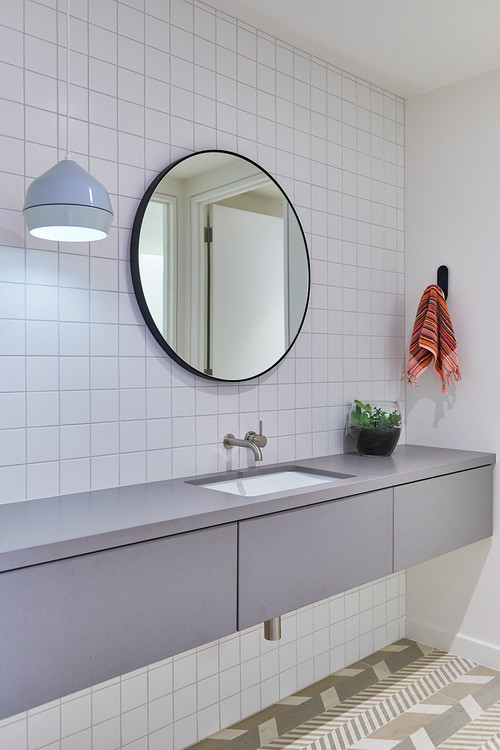 square tile splashbacks behind round mirror in bathroom