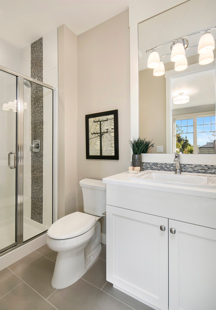 Idéer för amerikanska badrum med dusch, med vita skåp, en dusch i en alkov, en toalettstol med separat cisternkåpa, flerfärgad kakel, mosaik, beige väggar, klinkergolv i porslin, ett nedsänkt handfat, bänkskiva i akrylsten och luckor med infälld panel