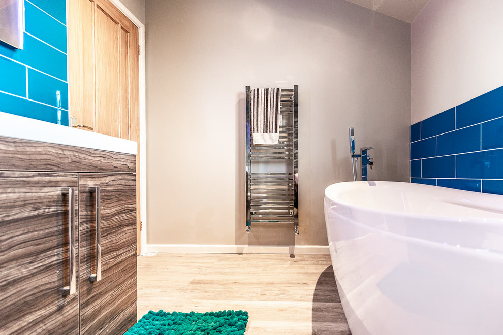 Aménagement d'une salle de bain principale moderne avec une baignoire indépendante, une douche d'angle, WC à poser, un carrelage bleu, un mur blanc, un sol marron et une cabine de douche à porte battante.