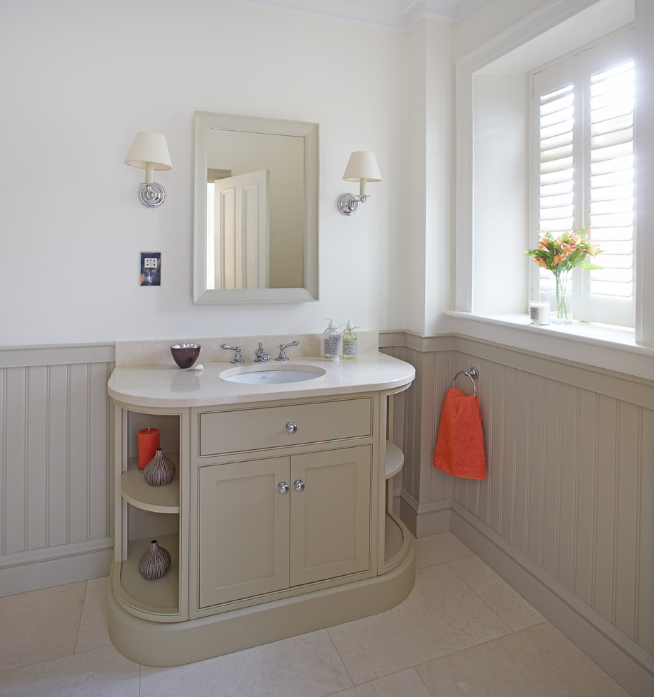 Idée de décoration pour une salle de bain champêtre de taille moyenne avec un mur blanc, un sol en carrelage de porcelaine, un lavabo encastré, un plan de toilette en marbre, un placard à porte affleurante et des portes de placard beiges.