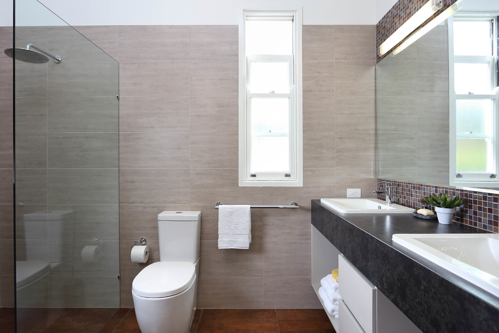 Inspiration för mellanstora moderna en-suite badrum, med ett nedsänkt handfat, öppna hyllor, grå skåp, laminatbänkskiva, en öppen dusch, en toalettstol med hel cisternkåpa, brun kakel, stenhäll, beige väggar och klinkergolv i porslin