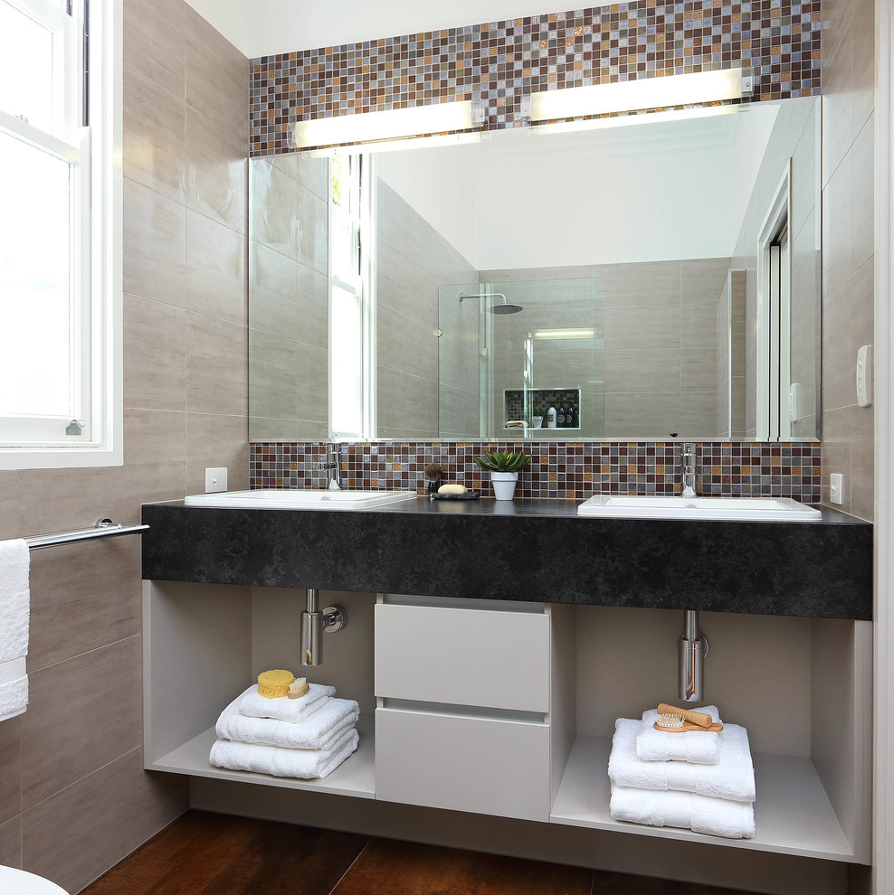 Modern inredning av ett litet badrum med dusch, med öppna hyllor, flerfärgad kakel, mosaik, ett nedsänkt handfat, grå skåp, en öppen dusch, vita väggar, klinkergolv i porslin och med dusch som är öppen