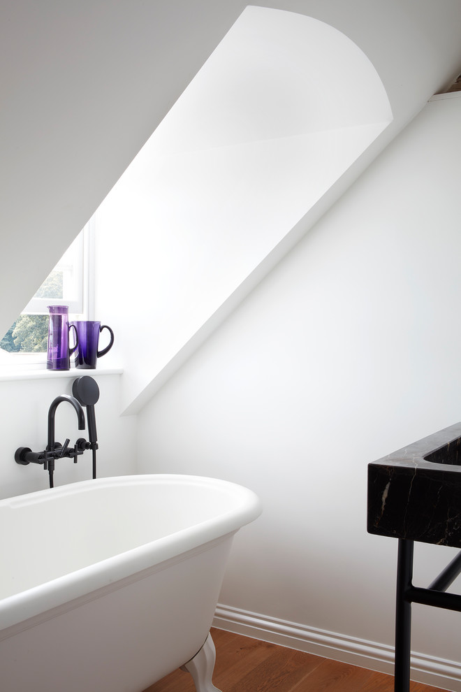 Inredning av ett modernt litet svart svart en-suite badrum, med ett badkar med tassar, en dusch/badkar-kombination, vita väggar, mellanmörkt trägolv, ett konsol handfat, marmorbänkskiva, brunt golv och med dusch som är öppen