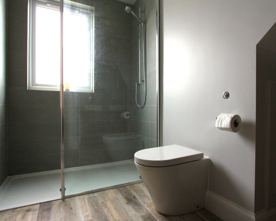 Design ideas for a small eclectic ensuite bathroom in Sussex with a vessel sink, freestanding cabinets, medium wood cabinets, wooden worktops, a built-in shower, a wall mounted toilet, grey tiles, ceramic tiles and brown walls.