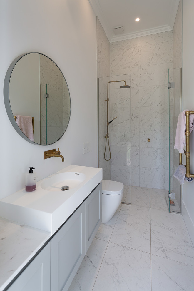 Inspiration for a small transitional 3/4 gray tile and marble tile marble floor and gray floor walk-in shower remodel in Auckland with gray cabinets, a one-piece toilet, white walls, marble countertops, a hinged shower door, white countertops, recessed-panel cabinets and an integrated sink