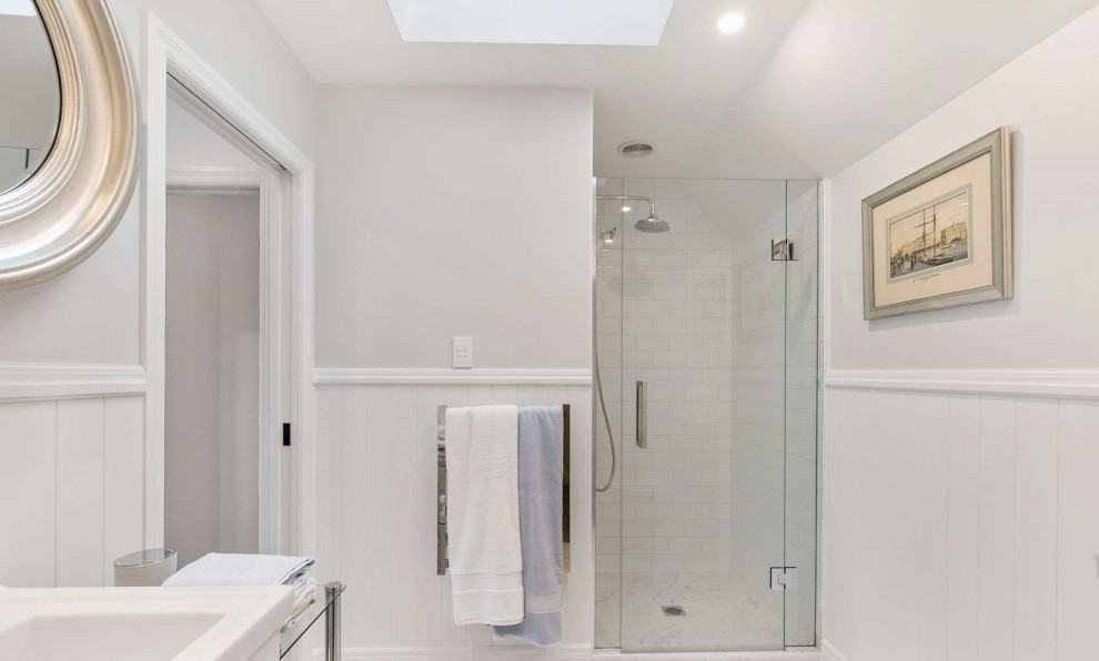 Exempel på ett litet vit vitt badrum med dusch, med vita skåp, en dusch i en alkov, en vägghängd toalettstol, vit kakel, keramikplattor, vita väggar, klinkergolv i keramik, ett integrerad handfat, laminatbänkskiva, vitt golv och dusch med gångjärnsdörr