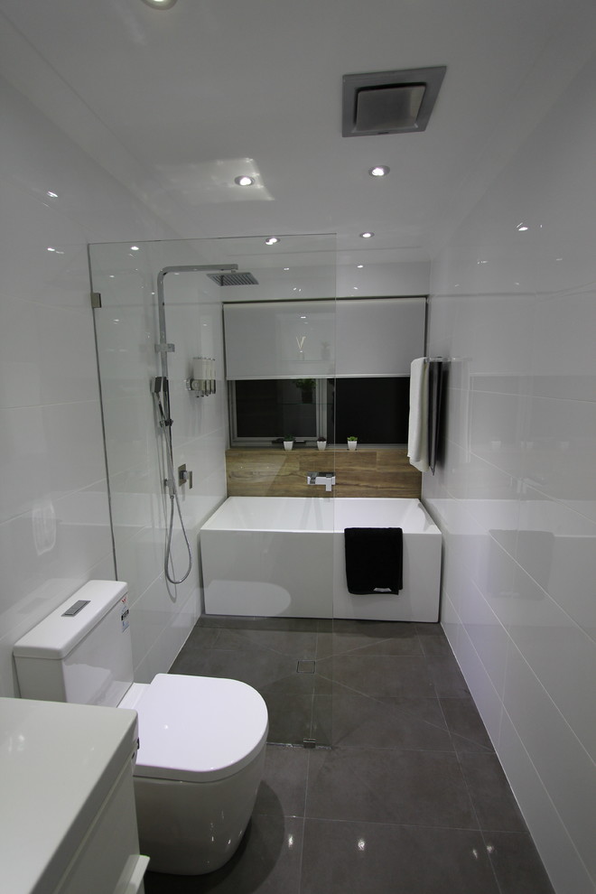 Cette photo montre une salle de bain principale moderne de taille moyenne avec un lavabo suspendu, une baignoire indépendante, une douche ouverte, WC séparés, un carrelage gris, des carreaux de porcelaine, un mur blanc et un sol en carrelage de porcelaine.