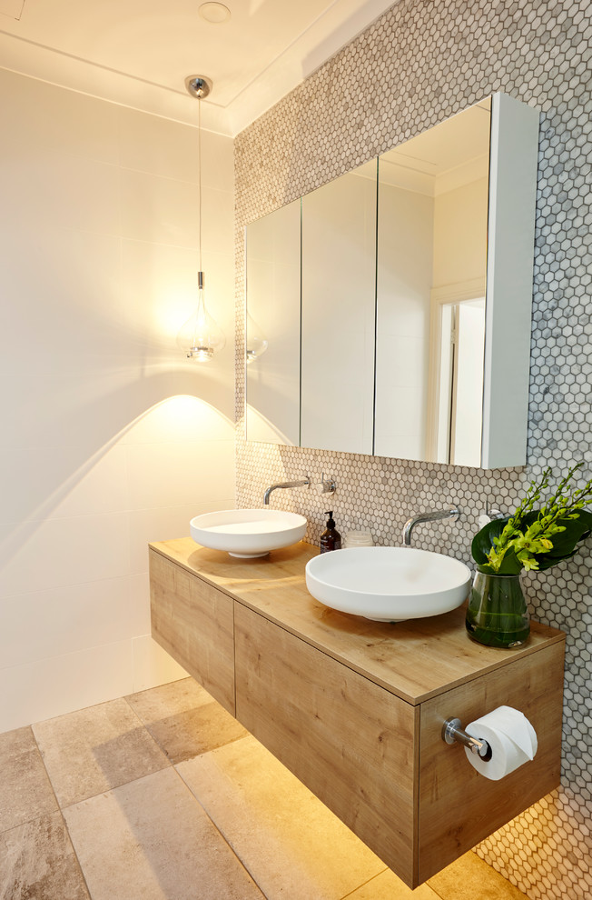 Modern inredning av ett mellanstort brun brunt en-suite badrum, med ett fristående handfat, skåp i mellenmörkt trä, mosaik, en toalettstol med hel cisternkåpa, grå kakel, vita väggar, klinkergolv i keramik, träbänkskiva, släta luckor, en dusch i en alkov och med dusch som är öppen