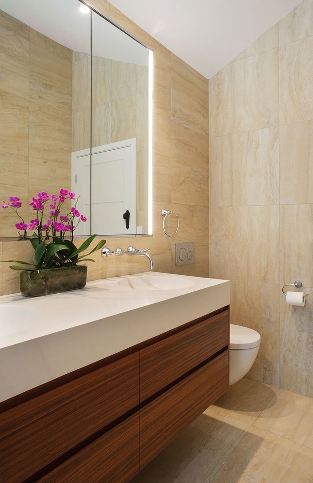 Inspiration for a medium sized modern ensuite bathroom in Brisbane with freestanding cabinets, medium wood cabinets, a built-in bath, a shower/bath combination, a one-piece toilet, beige tiles, ceramic tiles, beige walls, ceramic flooring, a wall-mounted sink, engineered stone worktops, beige floors and a hinged door.
