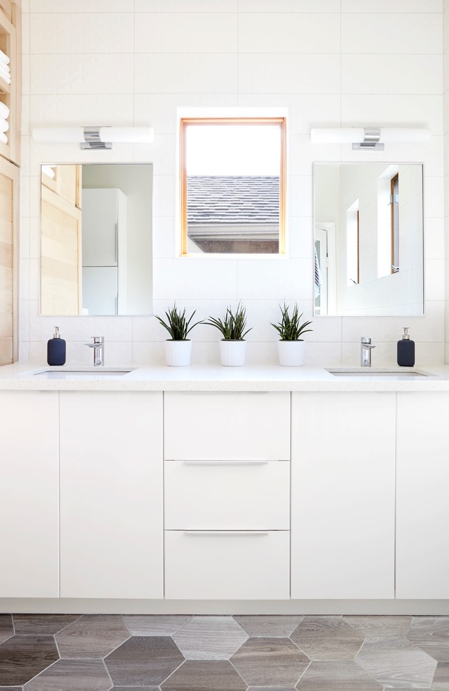 Idée de décoration pour une salle de bain principale design de taille moyenne avec un placard à porte plane, des portes de placard blanches, un carrelage gris, des carreaux de céramique, un mur blanc, un sol en carrelage de porcelaine, un lavabo encastré, un plan de toilette en quartz modifié, un sol marron et un plan de toilette blanc.