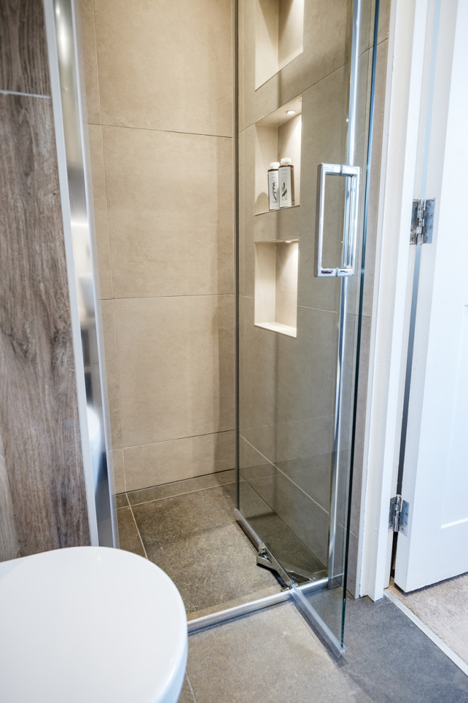 Idéer för att renovera ett litet funkis en-suite badrum, med släta luckor, skåp i mellenmörkt trä, en kantlös dusch, en vägghängd toalettstol, grå kakel, porslinskakel, grå väggar, klinkergolv i porslin, ett fristående handfat, laminatbänkskiva, svart golv och dusch med gångjärnsdörr