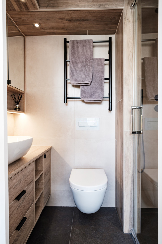 Idéer för ett litet modernt en-suite badrum, med släta luckor, skåp i mellenmörkt trä, en dusch i en alkov, en vägghängd toalettstol, grå kakel, porslinskakel, klinkergolv i porslin, ett fristående handfat, laminatbänkskiva och dusch med gångjärnsdörr