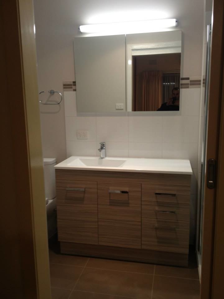Bild på ett litet funkis badrum med dusch, med luckor med profilerade fronter, bruna skåp, en dusch i en alkov, en toalettstol med separat cisternkåpa, vit kakel, keramikplattor, vita väggar, klinkergolv i porslin, ett integrerad handfat och bänkskiva i akrylsten